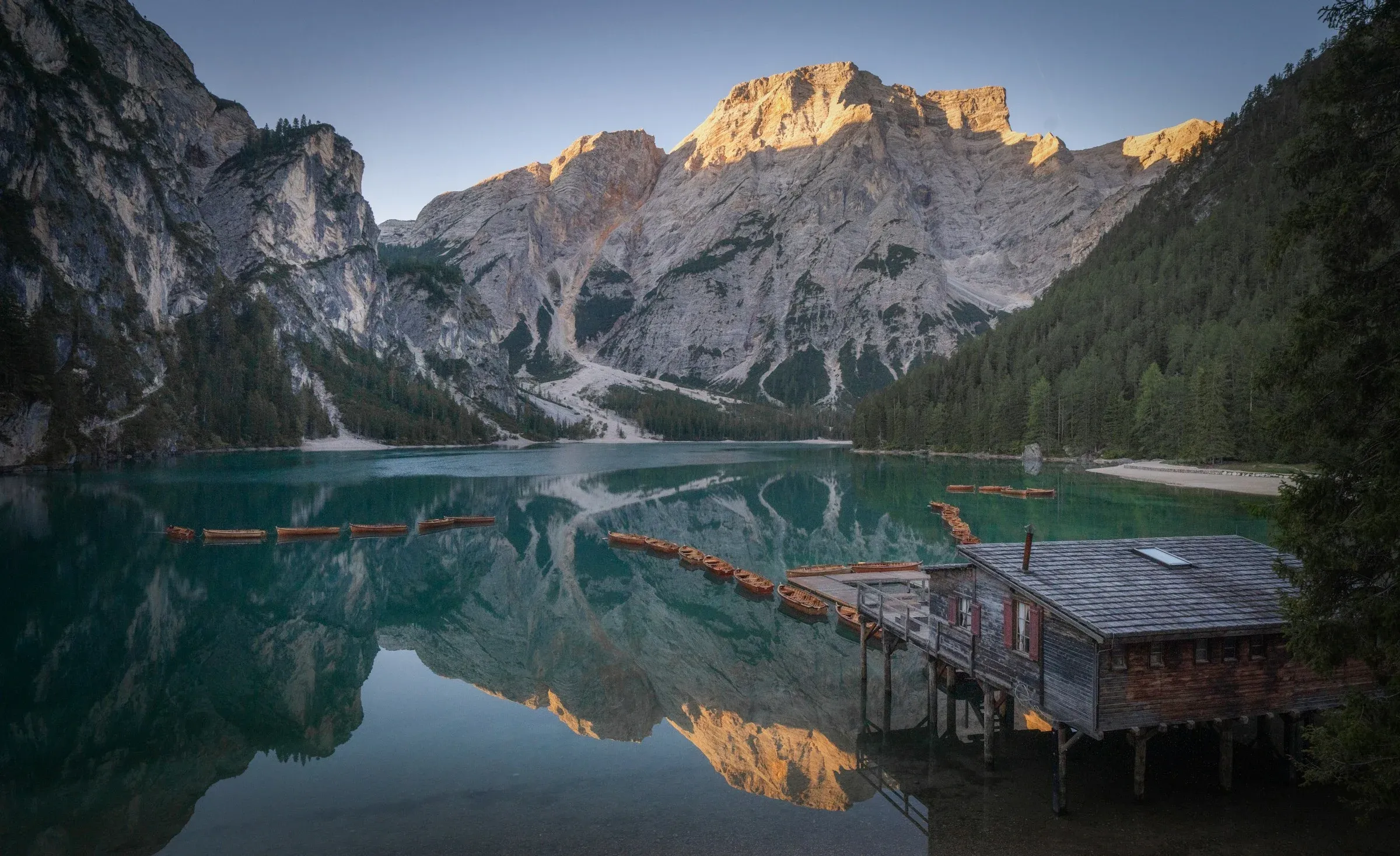 El lago di Braies, entre montañas, con su embarcadero de madera, editado en Lumen